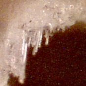 Poorly drilled PCB hole at 200x magnification, showing fibers