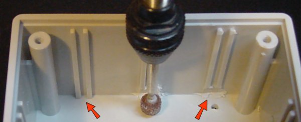 A Dremel rotary tool and grinding stone remove the bottom portion of project box slots to fit a PCB that lies flat.
