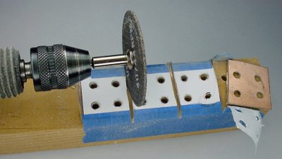 Cutting copper-clad switch brackets free with a Dremel cut-off disc.