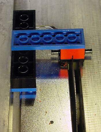 Table saw Lego jig cutting a slit in a Lego wheel plate