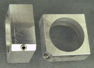 A square of aluminum with a motor hole drilled in the middle and a setscrew in the corner.