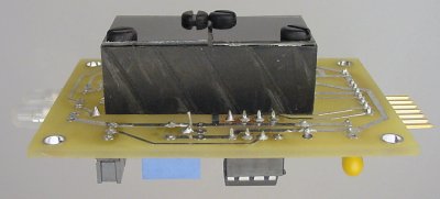 A double-sided PCB with a black plastic baffle and photosensors on one side, and other electronic components on the other side.