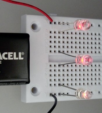 A single flashing LED causes two steady LEDs to blink at the same time on a solderless breadboard.