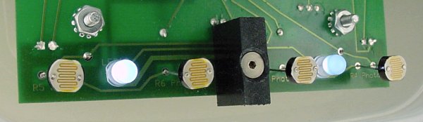 Black plastic block screwed into board to better separate light from each set of sensors