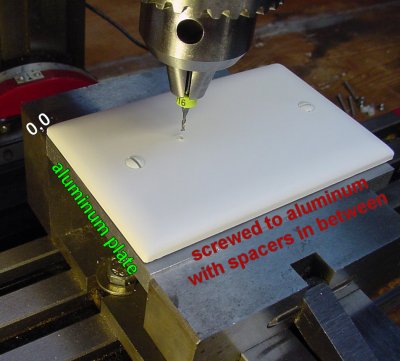 Blank wall plate mounted on aluminum stock in a milling machine vise.
